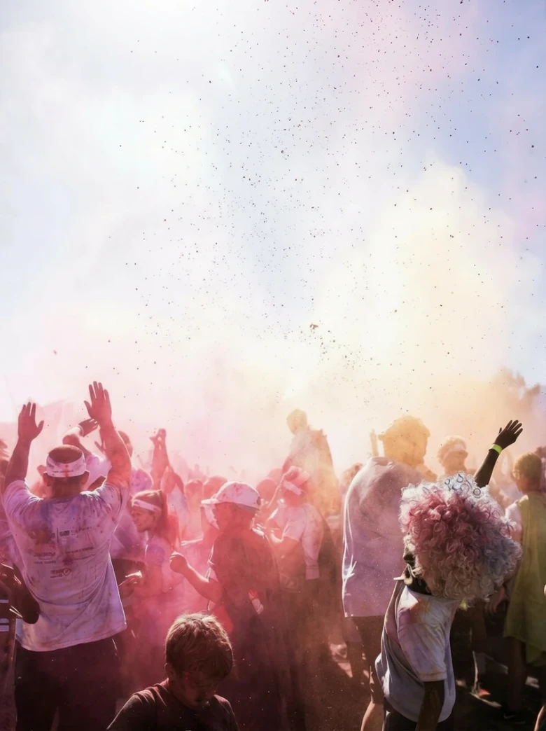 Una toma dinámica de una multitud eufórica en un gran festival de colores de Grandes Eventos Riojanos, cubiertos de polvo vibrante y bailando, con Catering Vicente como proveedor asociado.